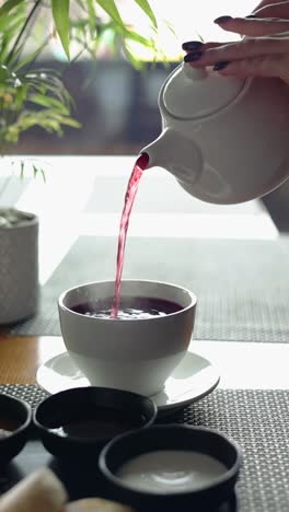 woman pouring hot red tea into a cup