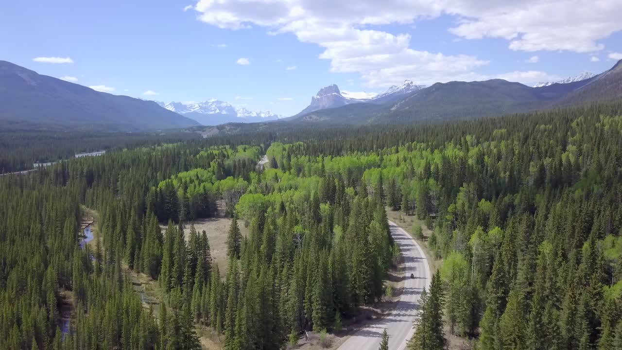 conducción de motocicletas en cimas de montañas cubiertas de nieve de ensueño y área de bosque de abetos verdes en canadá, antena