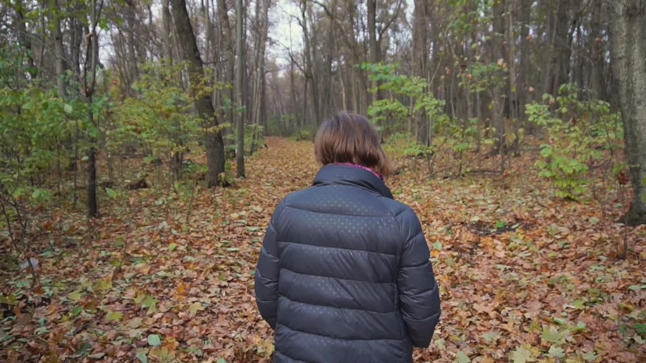 Donna che cammina nella foresta d'autunno