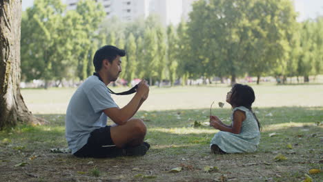 Happy-Asian-man-taking-photo-of-little-daughter-holding-flower