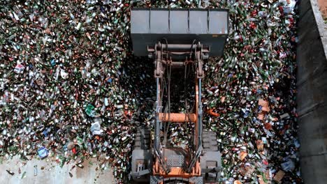 Forklift-excavator-is-pulling-glass-in-a-warehouse,-heavy-duty-machine-has-a-long-arm-fitted-with-a-glass-grabbing-attachment,-drone-view,-glass-recycling-in-a-processing-center-concept