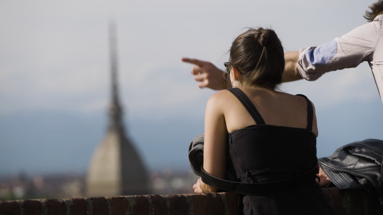 Una coppia di turisti che osserva lo skyline sfocato di Torino, Italia.