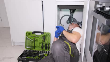a plumber in protective work clothes and gloves is doing plumbing work a plumber in protective work clothes and gloves is doing plumbing work replacing an old broken sink filter plumbing services