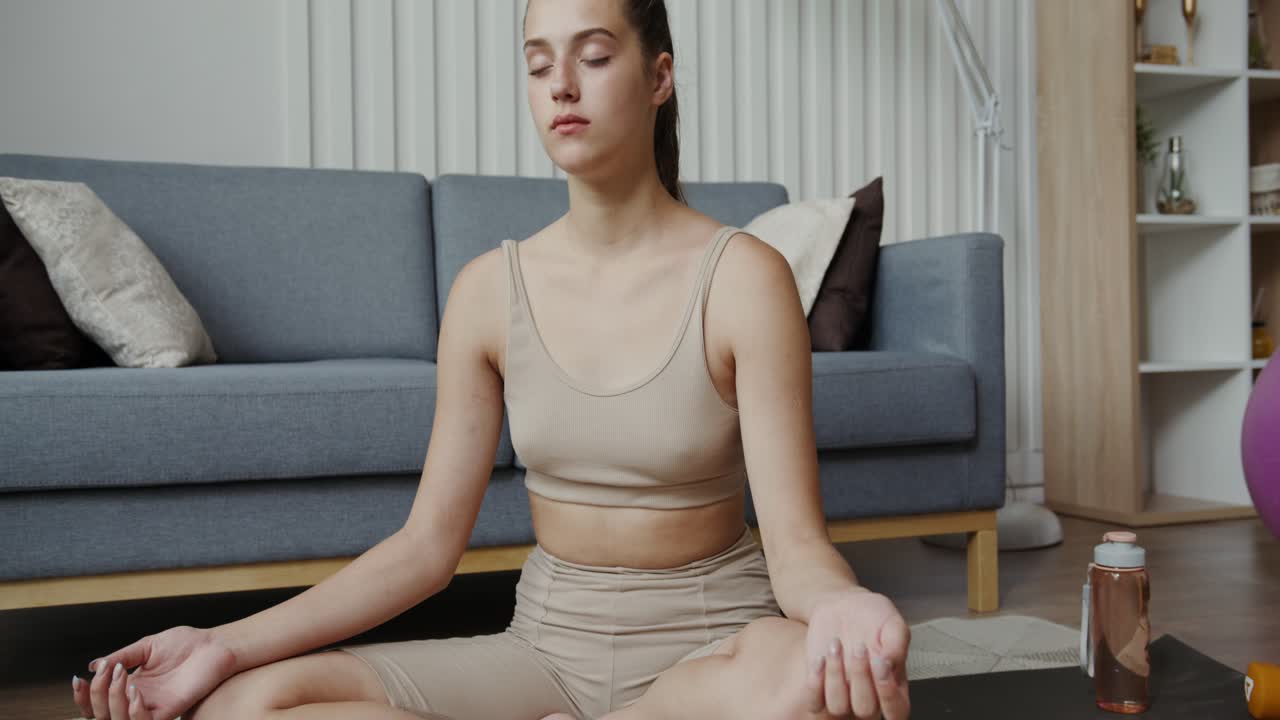 женщина практикует йогу и медитацию в своей гостиной.