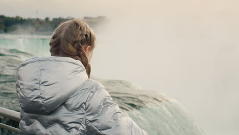 a girl in a warm jacket admires the majestic niagara falls