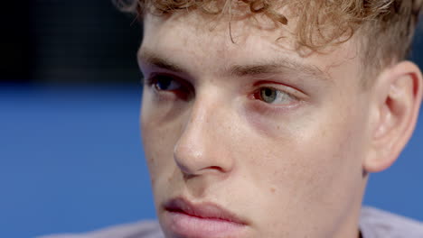 focused young man with curly hair concentrating intensely during padel tennis match, on indoor court