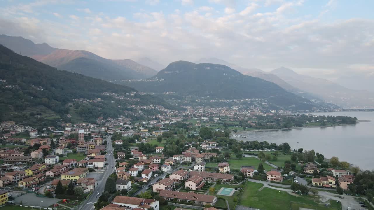 A captivating drone shot of the Italian town Dongo in Lake Como, captured from a unique angle. The footage highlights the town, majestic mountains, and serene waterfront scenery.