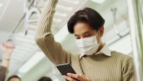traveler wearing face mask while using mobile phone on public train