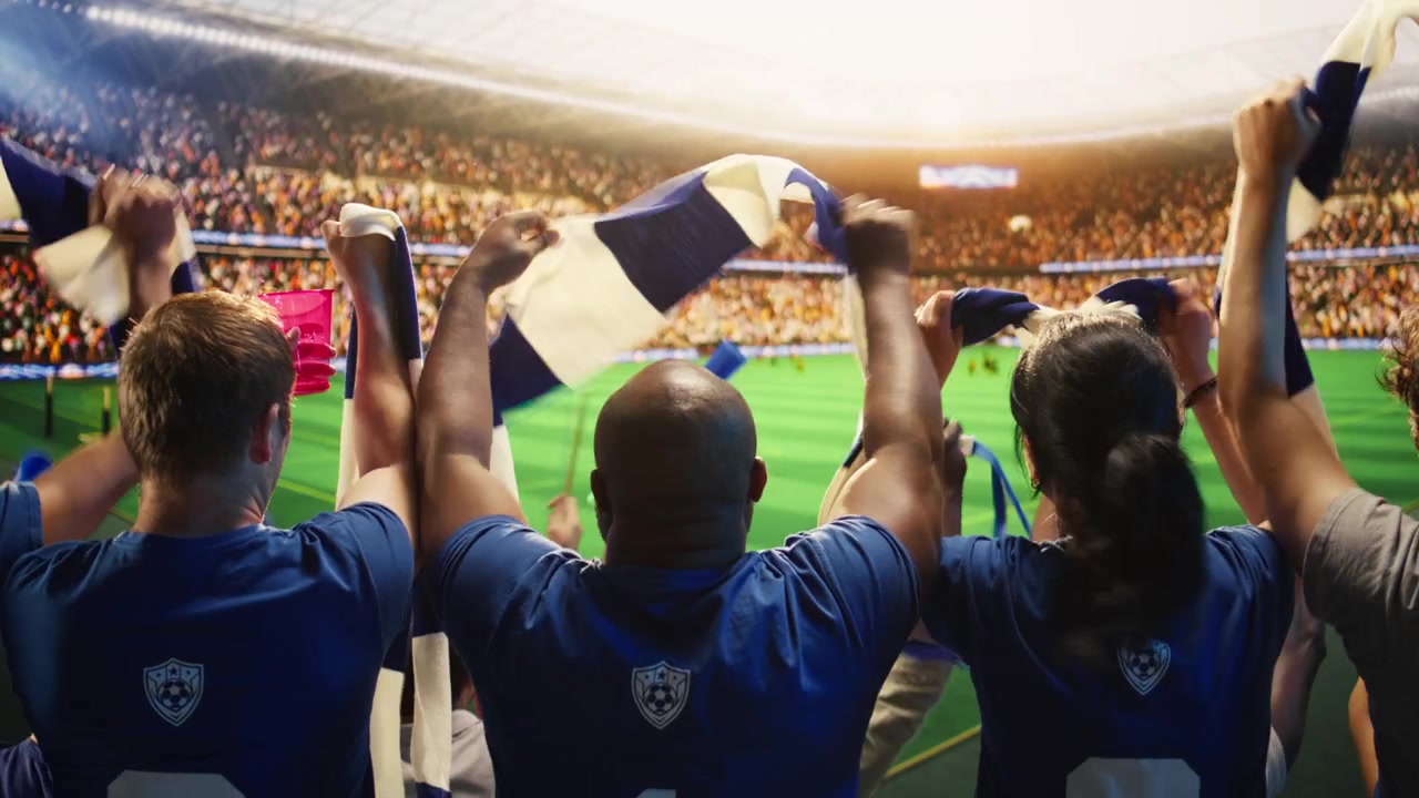 Primer plano de aficionados al fútbol sosteniendo bufandas en alto durante un partido de fútbol