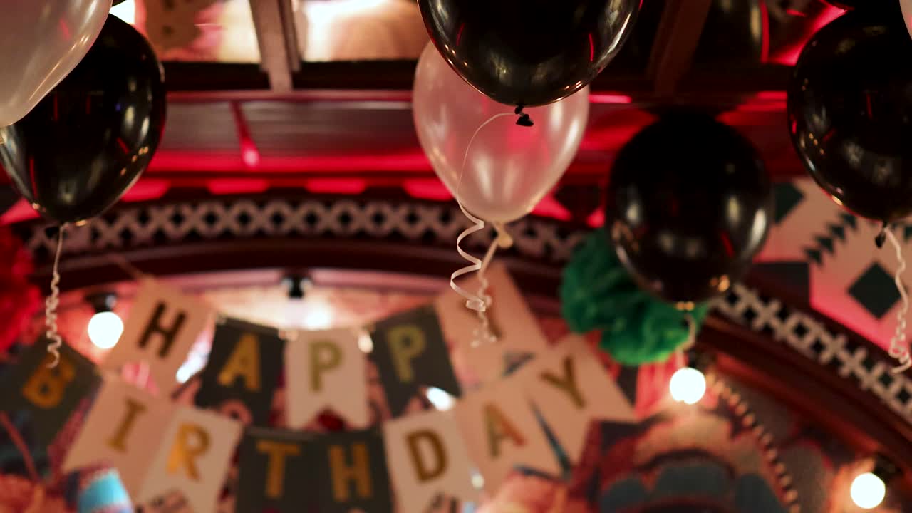 Colorful balloons and decorations create a festive birthday atmosphere in a Bangkok restaurant, captured with warm lighting and dynamic angles