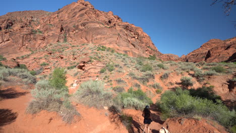 Ruta-De-Senderismo-De-St-George,-Utah-Usa,-Cámara-Lenta-De-Una-Joven-Excursionista-Bajo-Colinas-De-Arenisca-Roja-En-Un-Día-Caluroso-Y-Soleado,-Fotograma-Completo