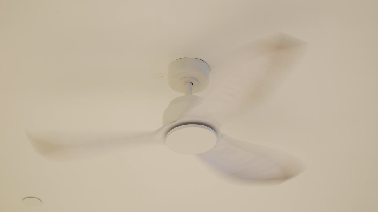 Ventilatore da soffitto bianco che gira su un soffitto semplice