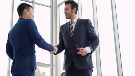 Business-people-handshake-with-friend-at-office