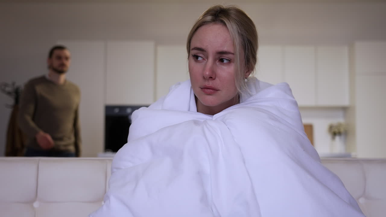 소파에 담요를 쓴 슬픈 여자