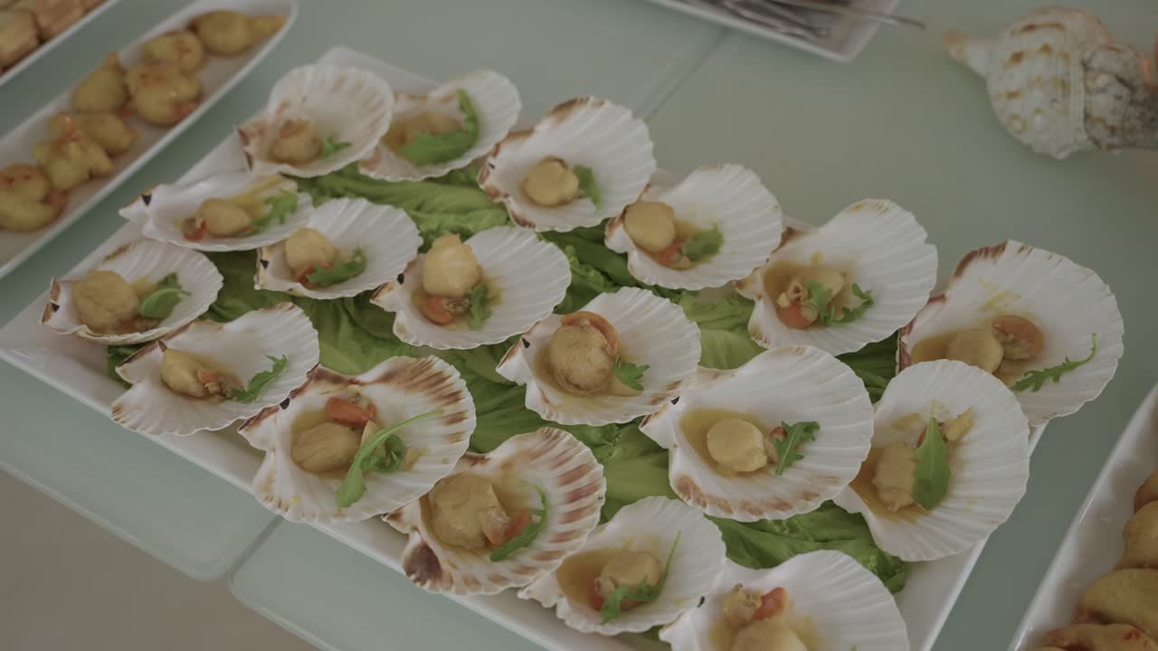 포르투갈식 피로연에서 신선한 채소 위에 천연 조개껍데기에 담긴 우아한 가리비 요리