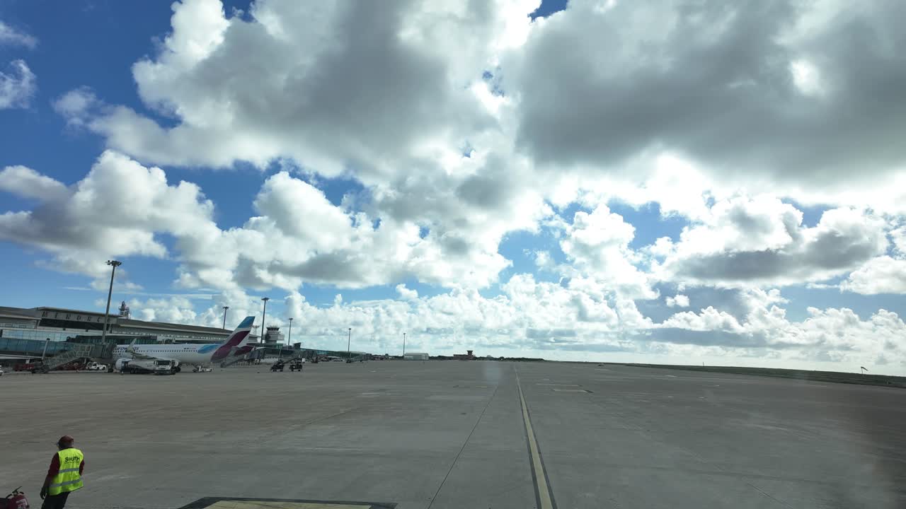 Passengers boarding to other plane during the pushback maneuver as seen from the cockpit, with a blue sky and some fluffy clouds.4K