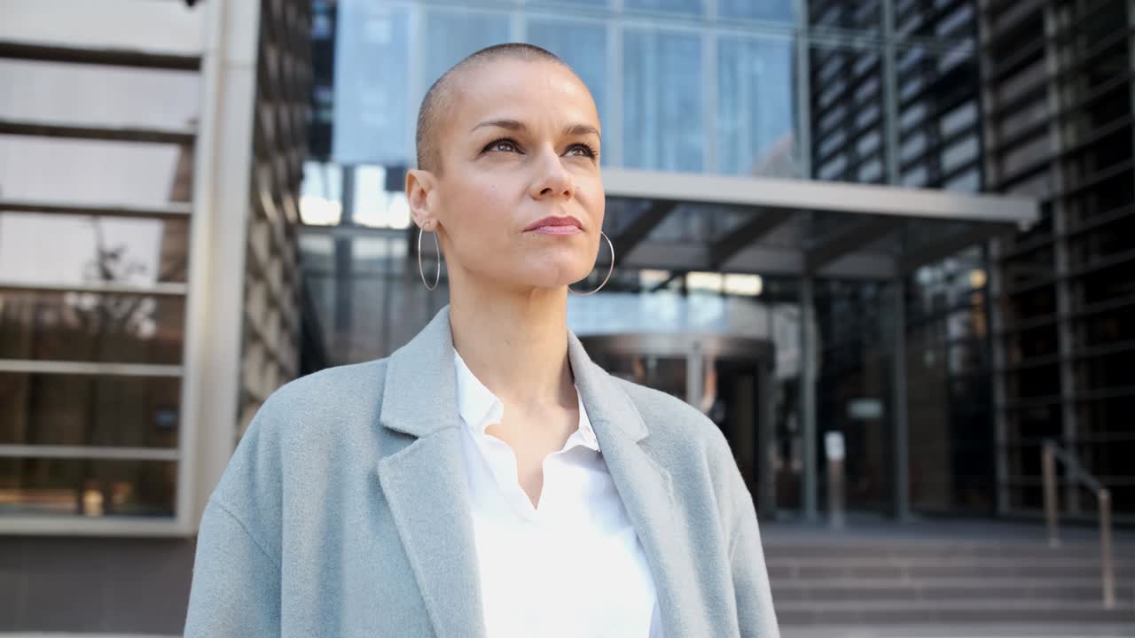 Donna d'affari sicura che distoglie lo sguardo mentre si trova all'aperto sulla strada nel quartiere della città finanziaria.