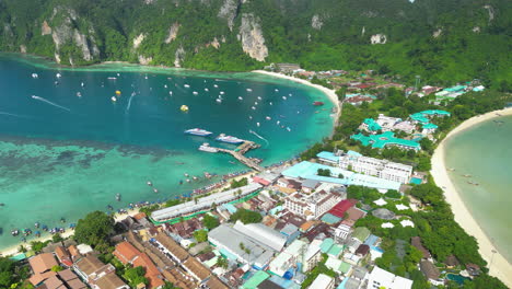 koh phi phi island harbor surrounded by tourist boats, passenger ferries, and hotels, aerial shot