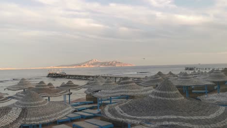 Lots-of-straw-umbrellas-on-a-sandy-beach-near-Red-Sea,-beach-holidays.