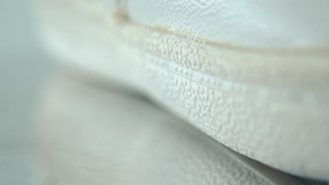 a macro close-up shot of a white sneaker sole, miniature shoe display on a 360 rotating stand with reflection, bright pattern texture, sport wear design, professional lighting, cinematic 4k video