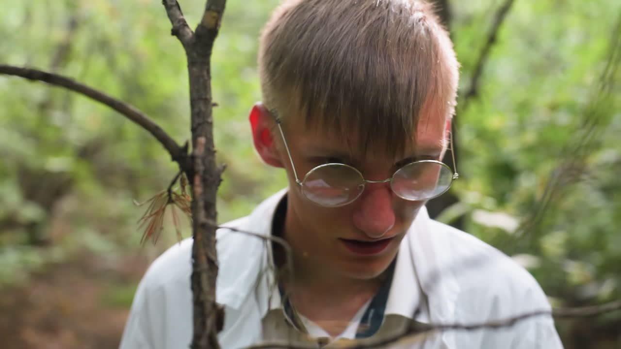Portrait view of scientific researcher in white coat conducting research and observing small stem with microscope in forest, focusing on ecological study, natural environment
