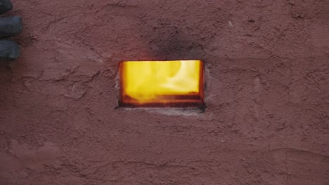 focus pull shot - potter removes a vent brick from a wood fired kiln to allow