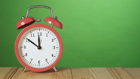 reloj de alarma rojo vintage en una mesa de madera natural sonando a las 12 horas. imágenes de pantalla verde. copia el espacio a la derecha.