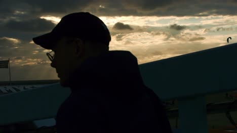 hombre con gorra camina hacia la playa de scheveningen durante la puesta de sol, en 1000 fps super slowmotion
