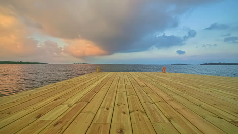 vista de cerca del viejo embarcadero de madera junto a un lago con movimiento de nubes blancas en el tiempo de la tarde