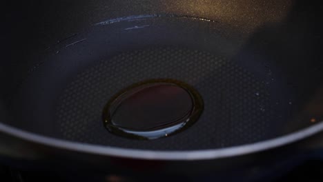 persona vertiendo aceite de una botella en una sartén