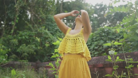 beautiful south asian girl flipping her hair and playing with her hair in a yellow outfit with a yellow top - a young beautiful south asian girl enjoying nature