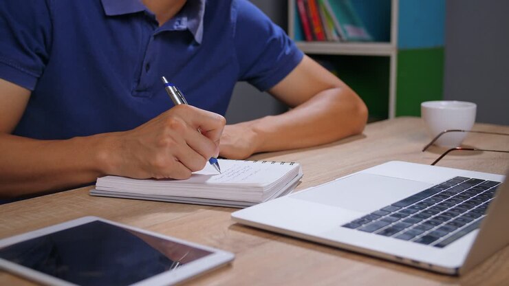 Person Writing Notes at a Desk