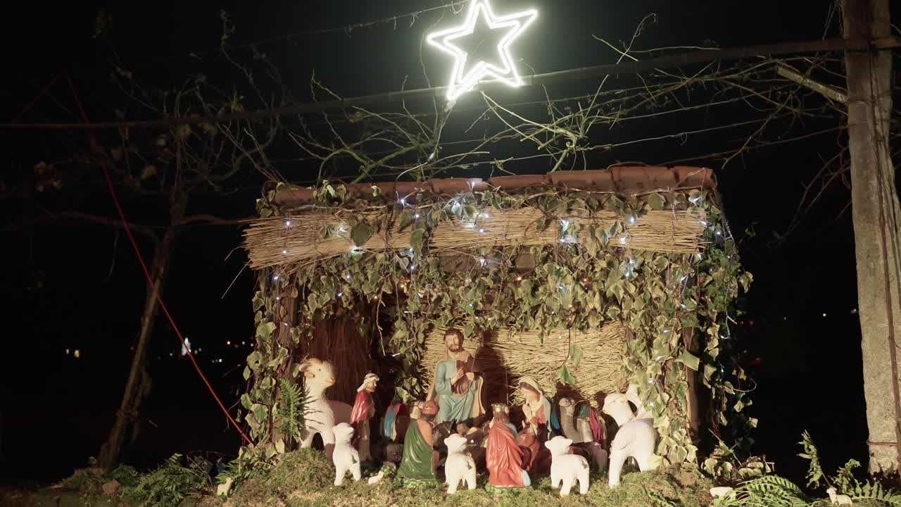 rustic outdoor nativity scene with Mary, Joseph, baby Jesus, and animals, lit by a glowing star at night