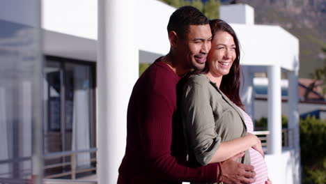 embracing outdoors, smiling couple with man holding pregnant woman's belly