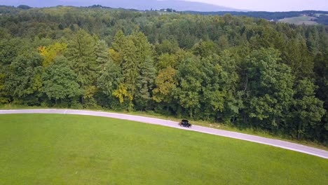 Vista-Aérea-Escénica-En-El-Viejo-Temporizador-Que-Viaja-En-La-Carretera-Al-Lado-Del-Bosque-Verde