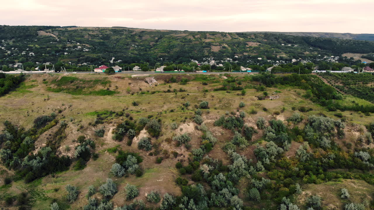 Aerial drone view overlooking a hillside village surrounded by greenery and agricultural fields