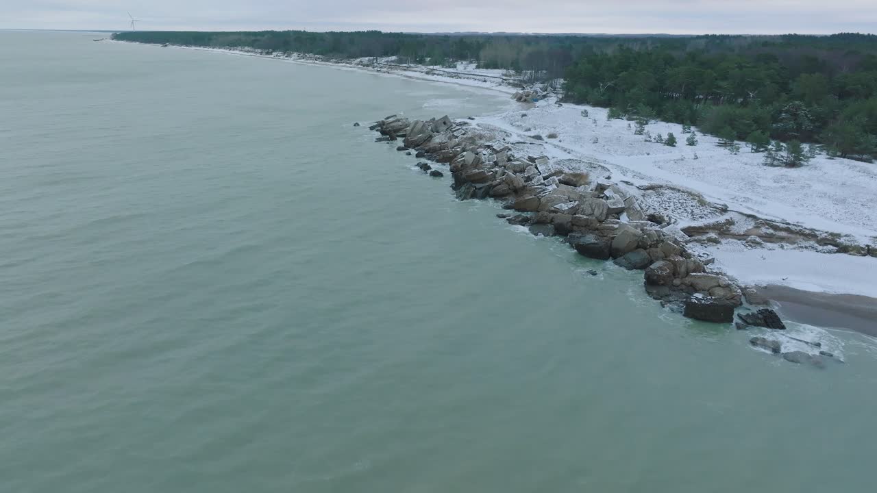Aerial establishing view of abandoned seaside fortification buildings at Karosta Northern Forts on the beach of Baltic sea , overcast winter day, distant drone shot moving forward
