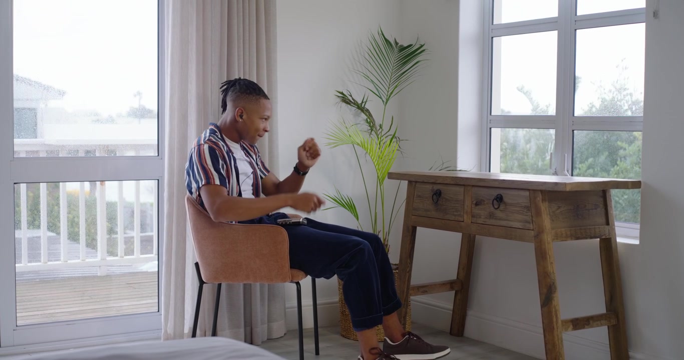 Uomo afroamericano che tiene un controller, muove i piedi e reagisce al feedback sullo schermo in camera da letto