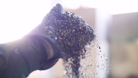 metal flakes fall from a gloved hand