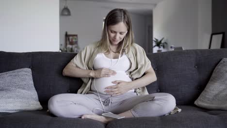 tranquil pregnant woman listening to music from smartphone