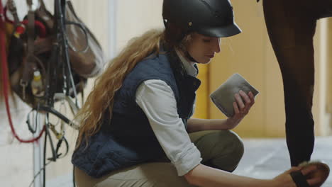 woman brushing and wrapping horse legs