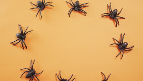 Close-up-of-multiple-spider-toys-with-copy-space-against-orange-background