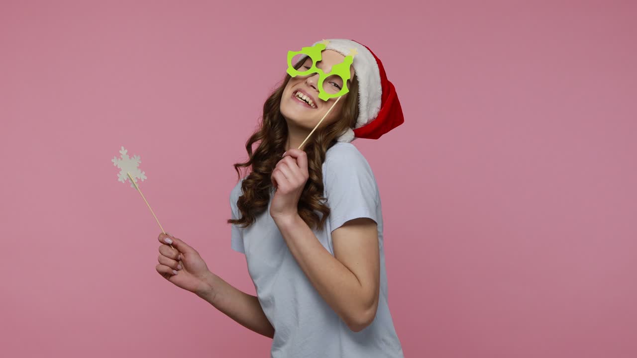 la chica con el sombrero de santa claus sostiene gafas de papel y copo de nieve.