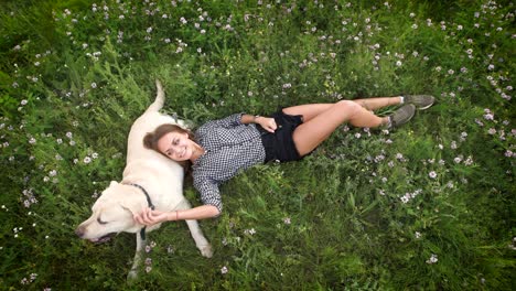 funny woman lay on the grass and plays with the dog