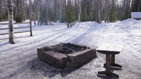 a cozy bonfire in a snowy forest near a cabin in rovaniemi, finland on a clear winter day