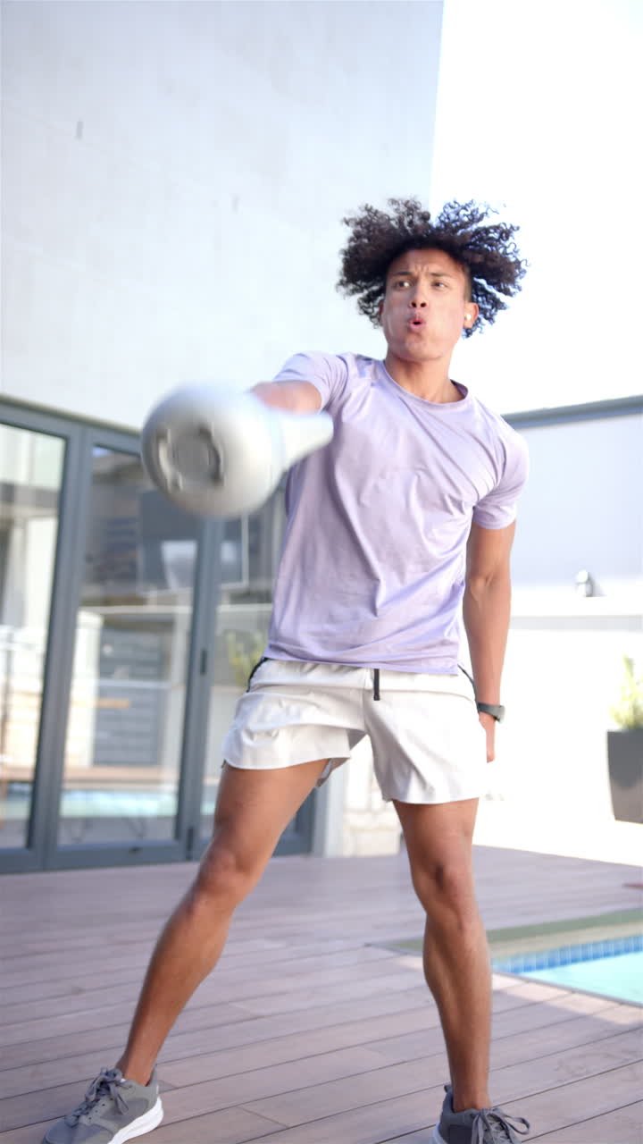 Video verticale: Un giovane uomo di etnia mista si allena con una kettlebell all'aperto