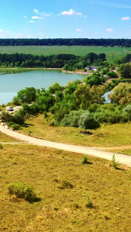 roads in the fields leading to the bridge over the narrow river. lush green nature in countryside in summer. top view. vertical video