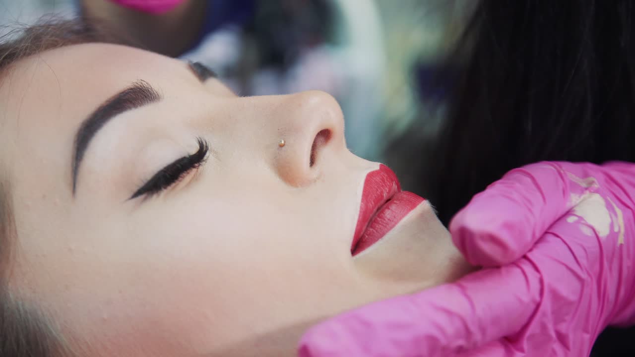 Creating a lip contour in a beauty salon. Close-up. Master in rubber gloves