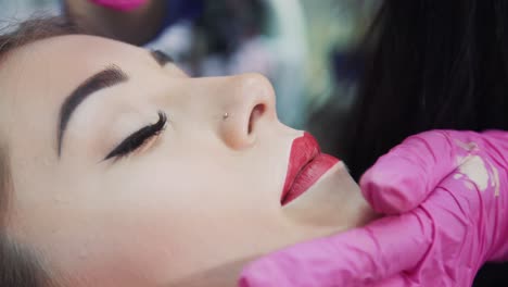 creating a lip contour in a beauty salon. close-up. master in rubber gloves