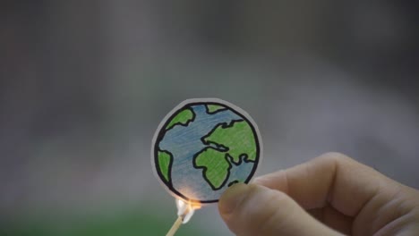 childish drawing of a world globe burning slowly while being held by hand